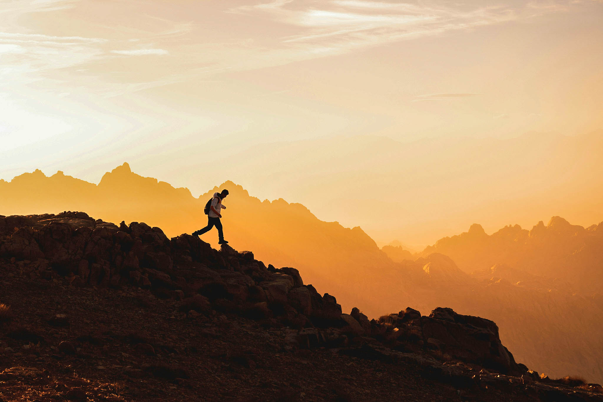 Hiker silhouetted against sunset mountains